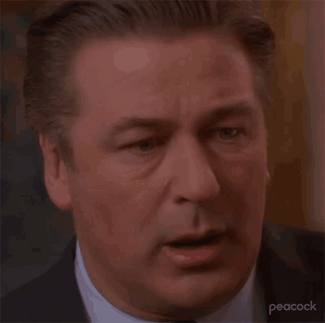 a close up of a man 's face in a suit and tie with his mouth open .