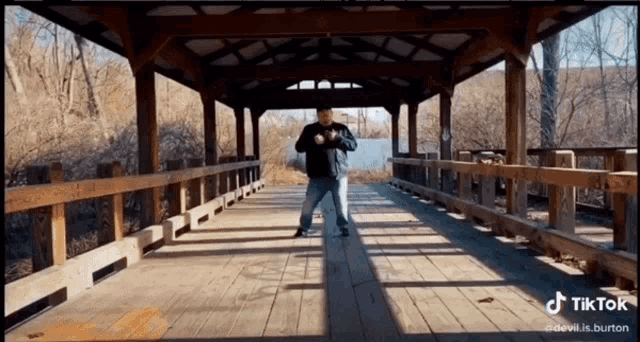 a man stands on a wooden bridge with a tiktok watermark