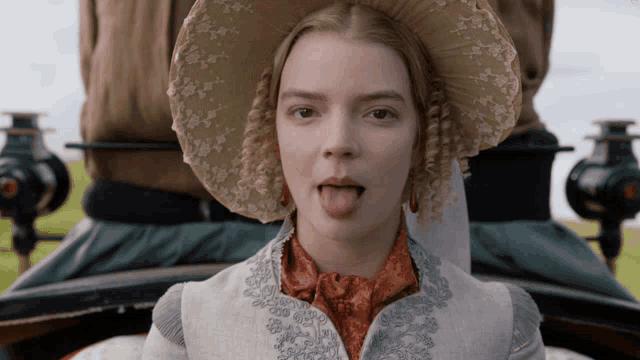 a woman sticking her tongue out wearing a hat