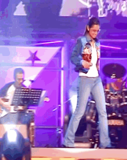 a woman stands on a stage in front of a drum set that says ' yamaha ' on it
