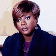 a woman is making a funny face while wearing a purple shirt and earrings .