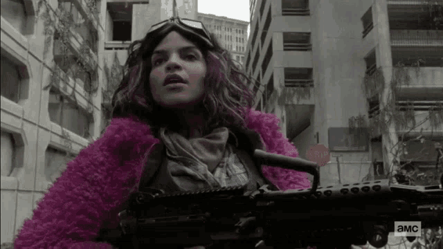 a woman in a pink coat is holding a gun in front of a sign that says stop