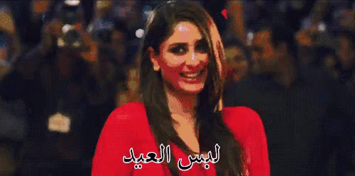 a woman in a red dress is smiling with arabic writing behind her