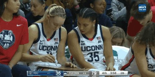 two uconn basketball players are sitting in the stands