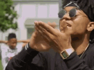 a man wearing sunglasses and a headband is holding his hands together .