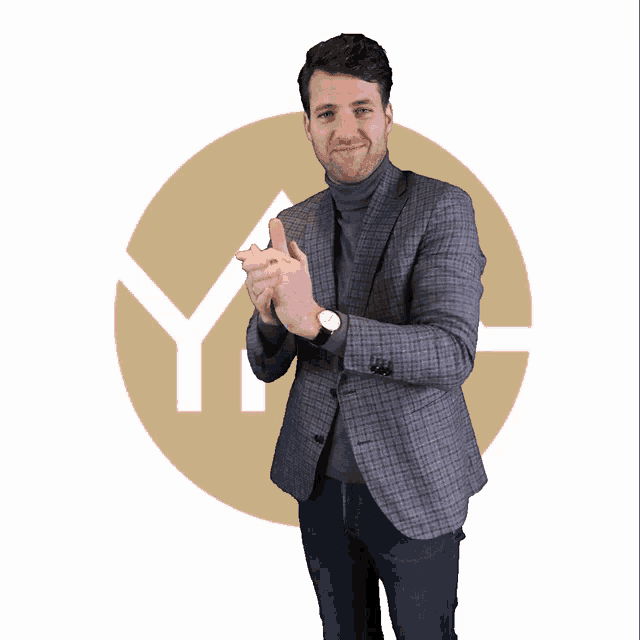 a man in a suit and turtleneck stands in front of a circle with the letter y in it