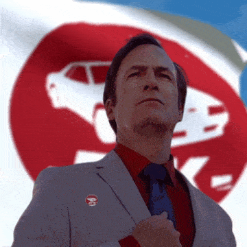 a man in a suit and tie has a pin on his jacket that says i 'm a car guy