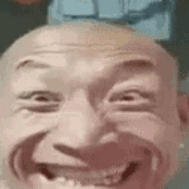 a close up of a bald man making a funny face and smiling .
