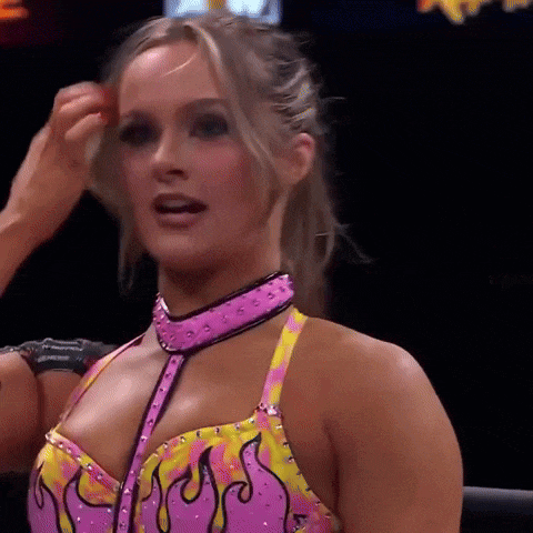 a woman in a pink and yellow outfit is standing in a wrestling ring .