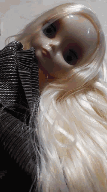 a doll with long blonde hair is wearing a sweater