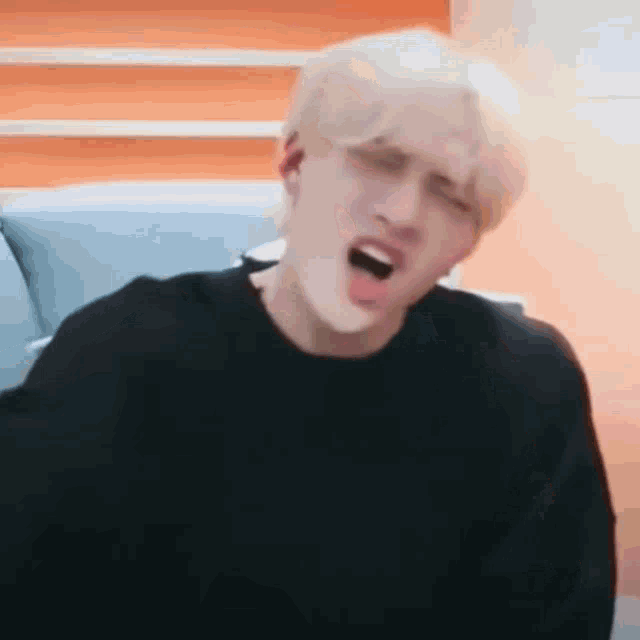a man is sitting on a couch with his mouth open and his tongue sticking out .