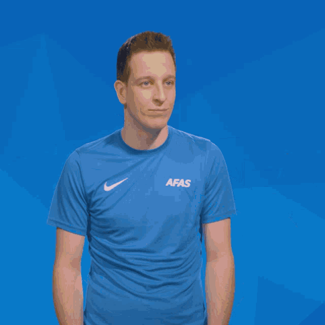 a man wearing a blue afas shirt has a pie thrown at his face