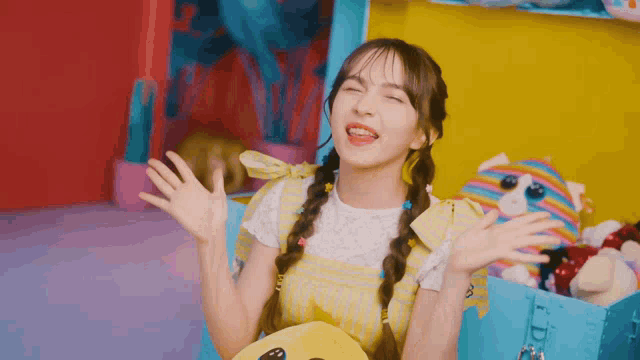 a girl in a yellow dress is holding a stuffed animal in her hands
