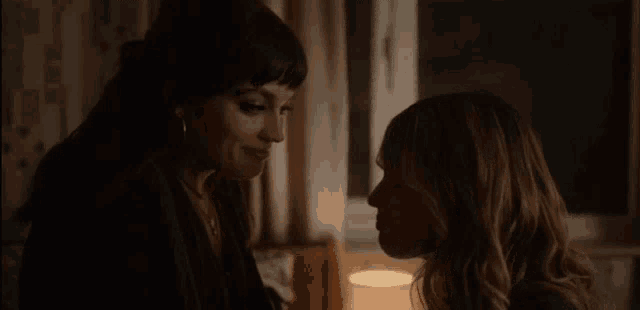 two women are looking at each other in a dark room in a room .