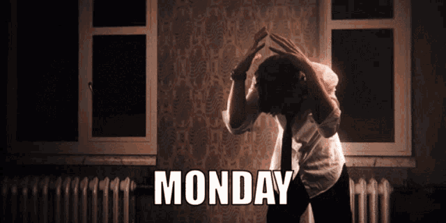 a man in a white shirt and tie is standing in front of a wall with monday written on it