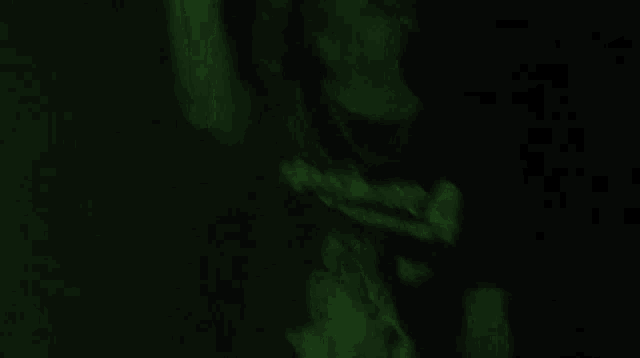 a close up of a person 's face in a dark room with a green light shining on it .