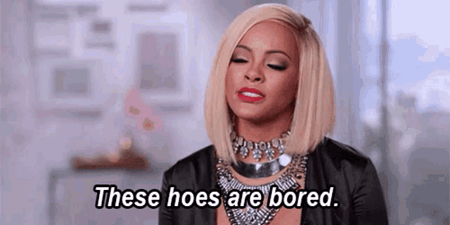 a woman is wearing a necklace and a black jacket and says `` these hoes are bored . ''