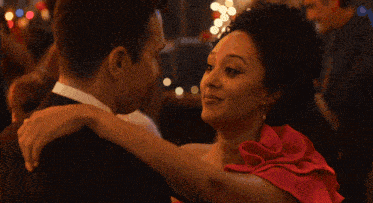 a man in a tuxedo and a woman in a red dress are dancing