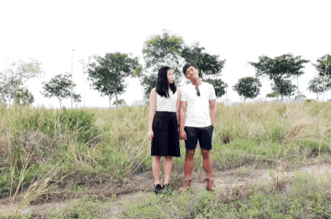 a man and a woman are holding hands in a field