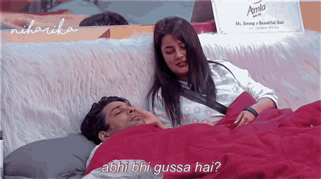 a man and a woman are laying in bed with a sign that says amla on the wall