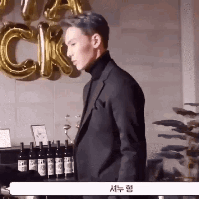 a man in a suit is standing in front of a display of wine bottles