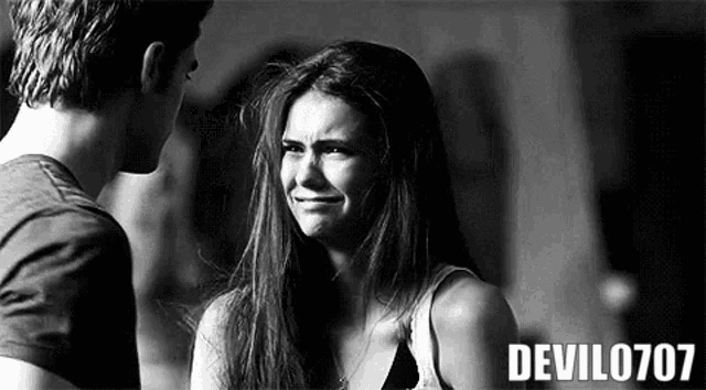 a man and a woman are looking at each other in a black and white photo . the woman is crying .