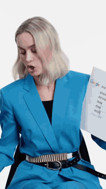 a woman in a blue suit is holding up a google brief