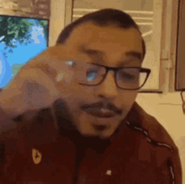 a man with glasses and a mustache is wearing a red jacket and a red shirt .