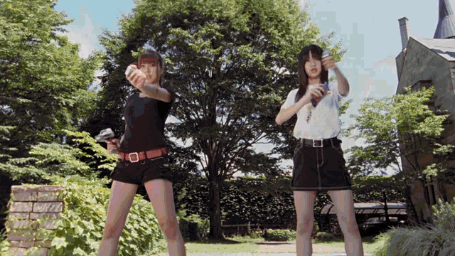 two women are standing in a park holding guns in their hands