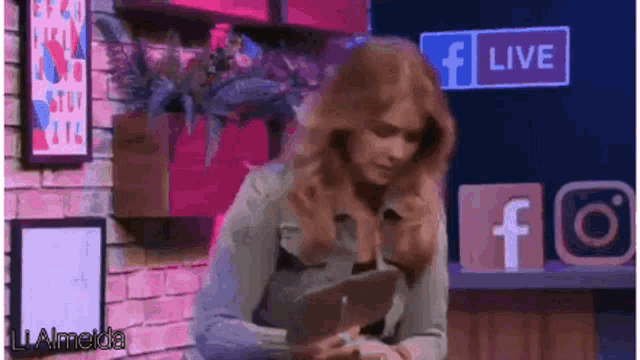 a woman is using a tablet in front of a facebook live sign