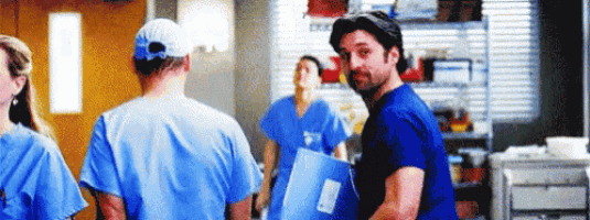 a group of doctors and nurses are standing in a hallway .