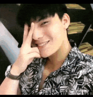 a young man is making a peace sign with his hands .