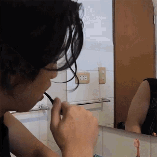a person brushing their teeth in front of a bathroom mirror