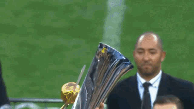 a man in a suit holds a trophy in his hand