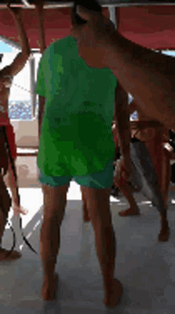 a man in a green shirt is standing in front of a group of people on a boat