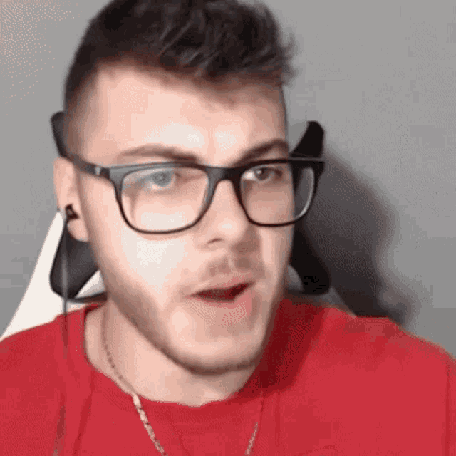 a close up of a man wearing glasses and a red shirt .