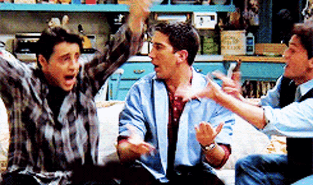 a group of men are sitting on a couch with their hands in the air