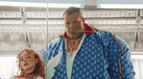 a man and a woman are standing next to each other and the man is wearing a blue gucci jacket