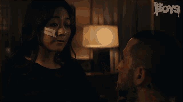 a woman with a bandage on her face is looking at a man with the words the boys on the bottom