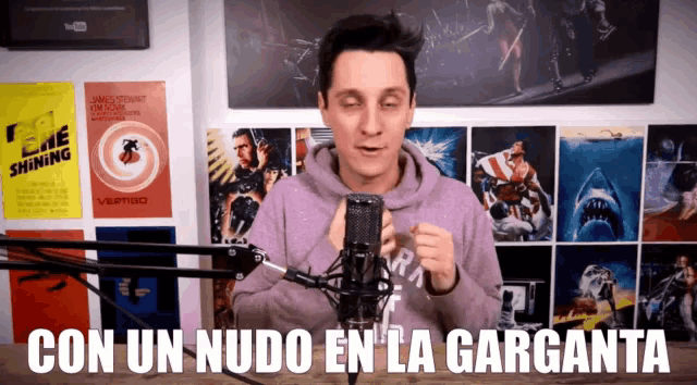 a man stands in front of a microphone with the words con un nudo en la garganta behind him