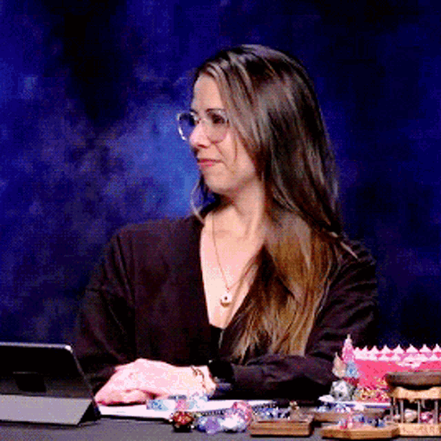 a woman wearing glasses is sitting at a desk with a tablet