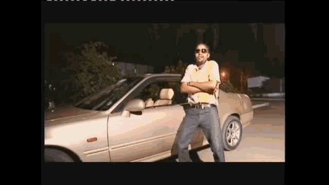 a man in sunglasses is standing in front of a car .