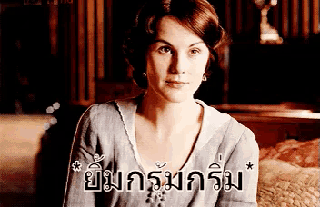 a woman is sitting on a bed with a foreign language written on the bottom of her face .