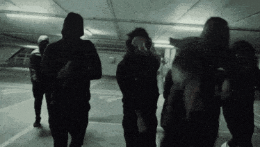 a group of people are standing in a parking garage .