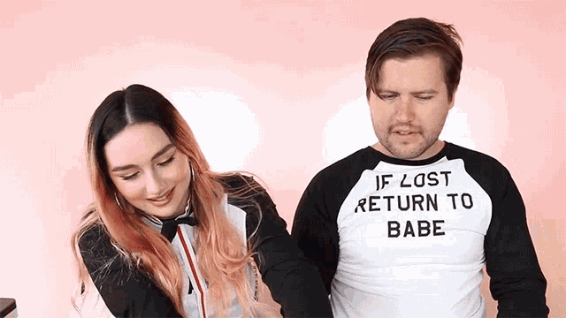 a man wearing a shirt that says if lost return to babe is standing next to a woman