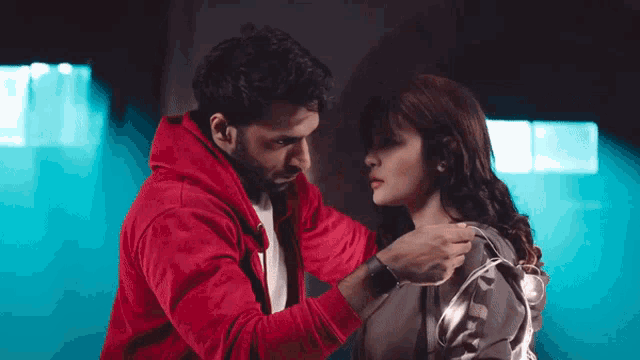 a man in a red hoodie is helping a woman with her jacket