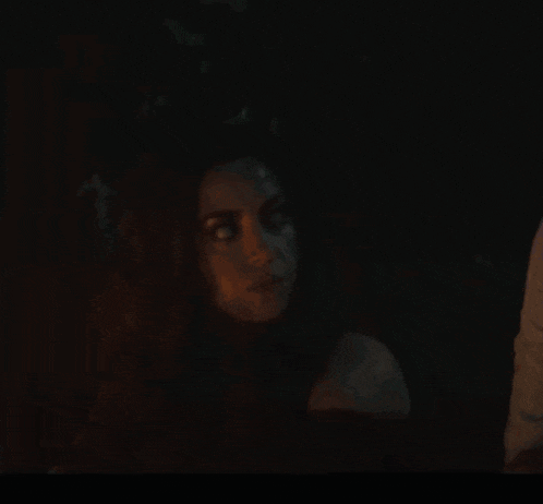 a woman in a dark room with a man behind her