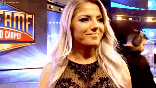 a woman in a black dress is smiling in front of a sign that says fame d carpet .
