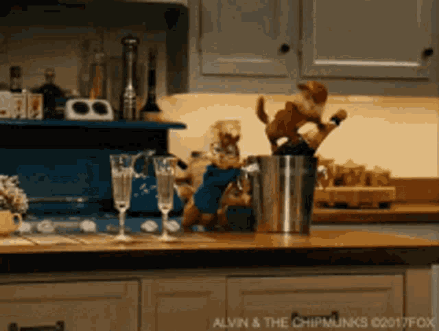 a chipmunk is standing on a kitchen counter next to a bucket of champagne glasses