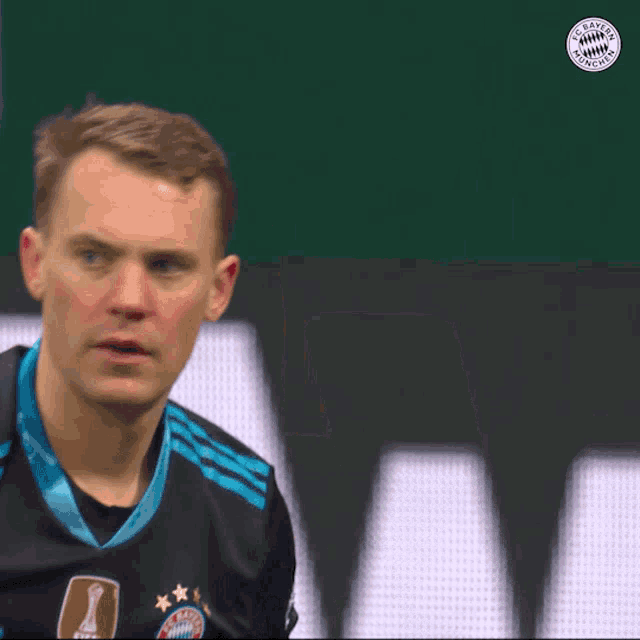 a man wearing a bayern munich jersey stands in front of a green background